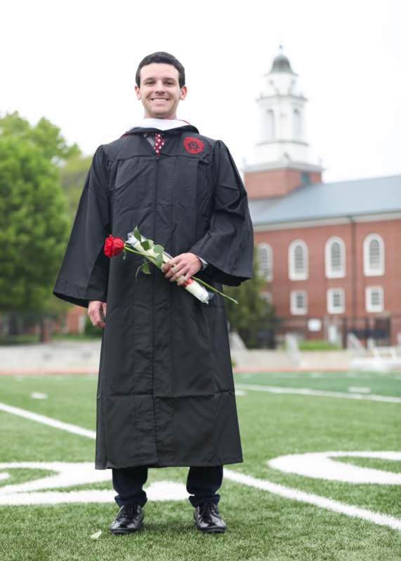 a man in a graduation gown holding a rose