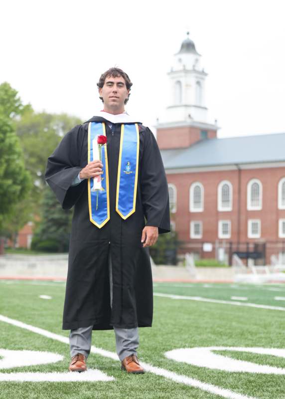 a man in a graduation gown holding a rose