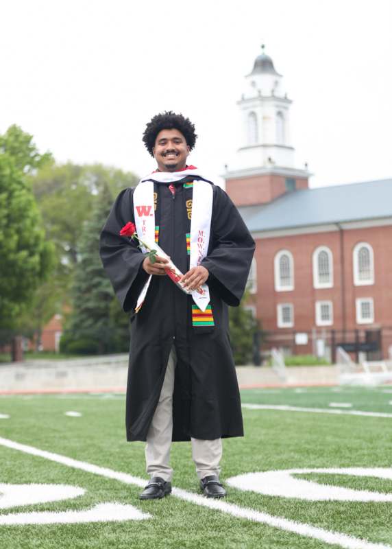 a man in a graduation gown holding a rose