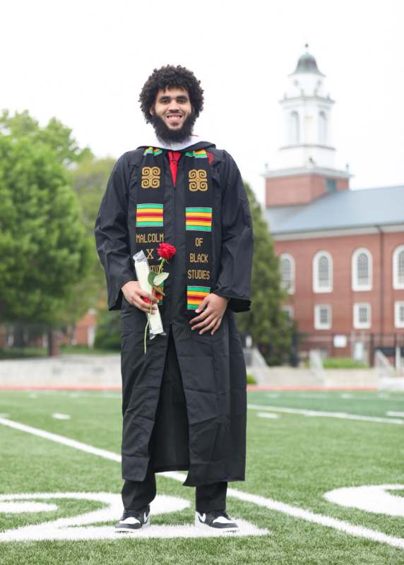 a man wearing a graduation gown and holding a rose