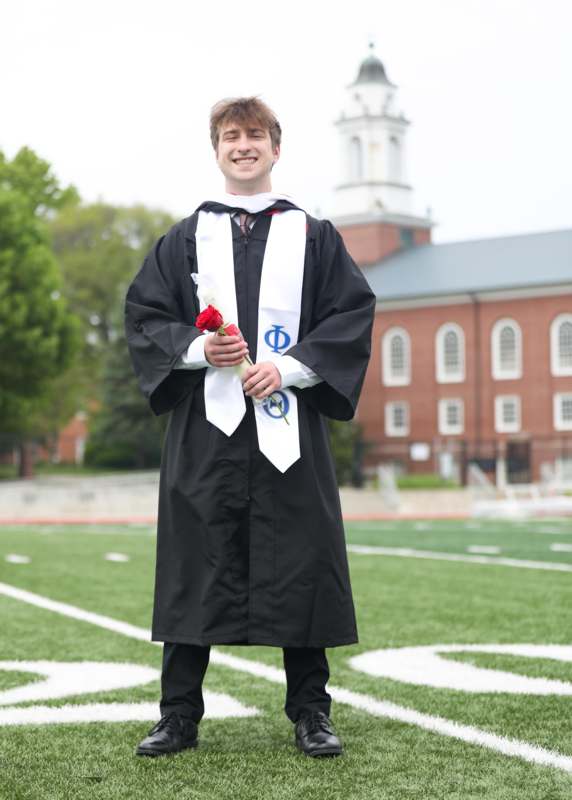 a man in a graduation gown holding a rose