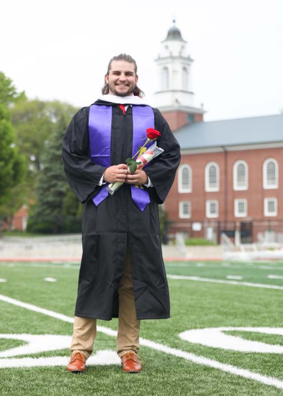 a man in a graduation gown holding a rose