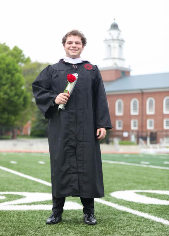 a man in a graduation gown holding a rose