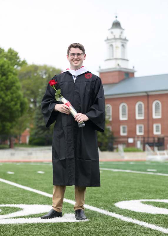 a man in a graduation gown holding a rose