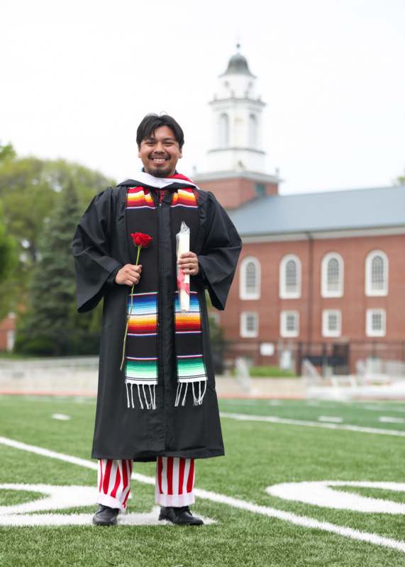 a man in a graduation gown holding a rose
