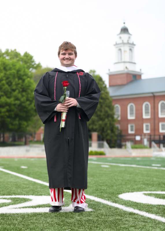 a man in a graduation gown holding a rose