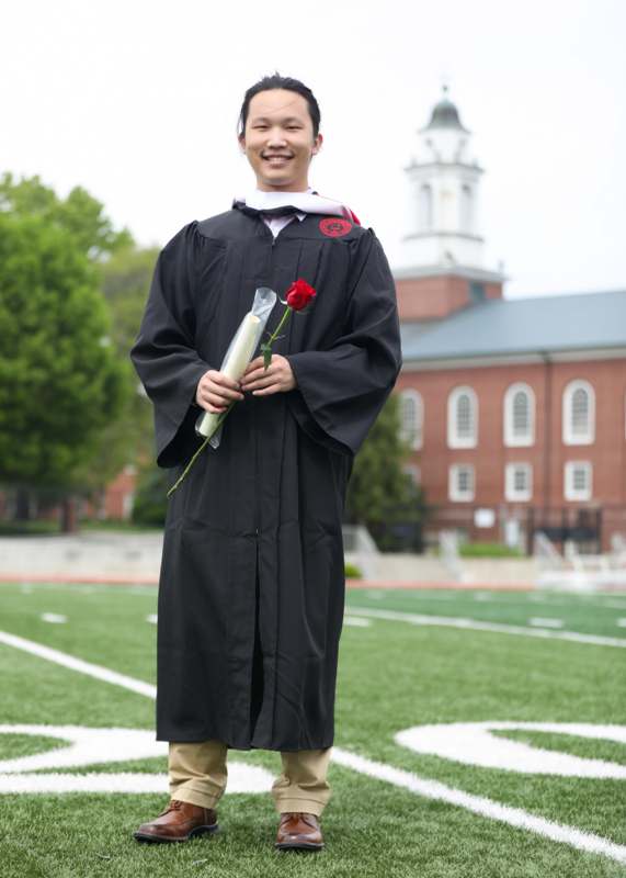 a man in a graduation gown holding a rose