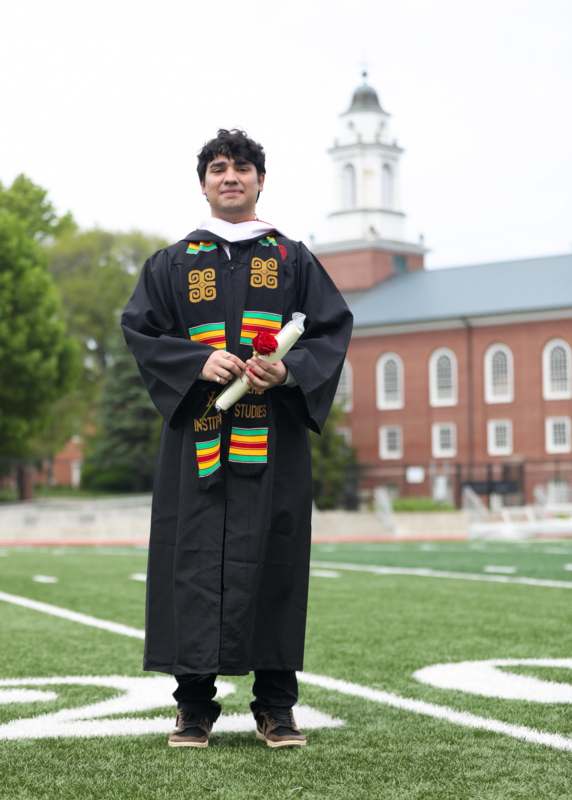 a man in a graduation gown holding a rose