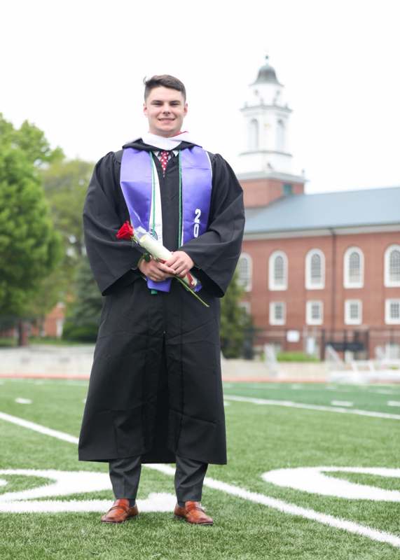 a man in a graduation gown holding a rose
