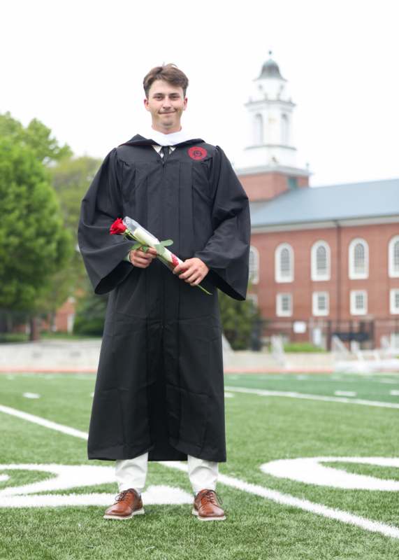 a man in a graduation gown holding a rose