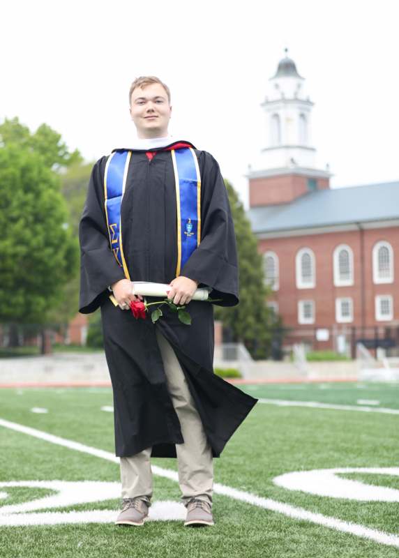 a man in a graduation gown holding a rose