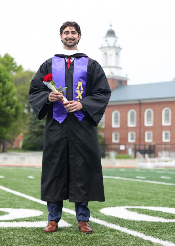 a man in a graduation gown holding a rose
