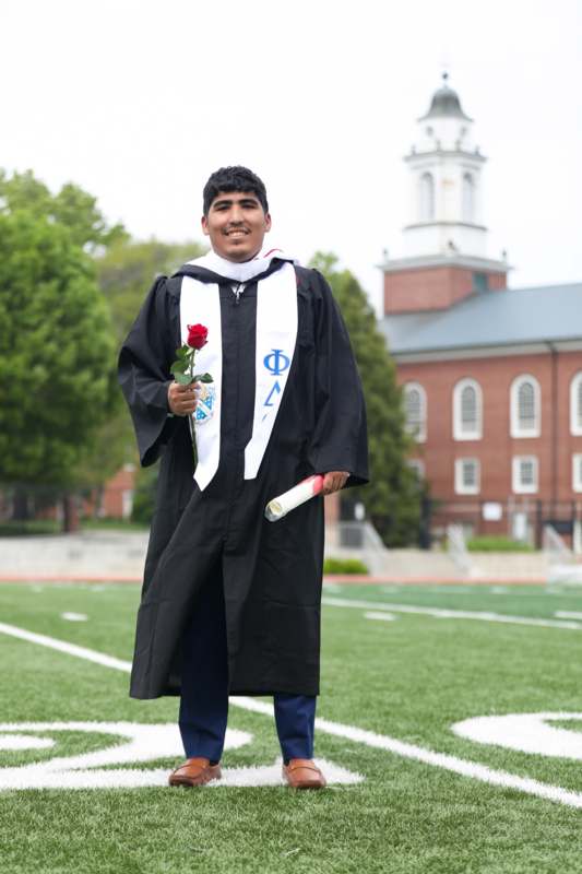 a man in a graduation gown holding a rose
