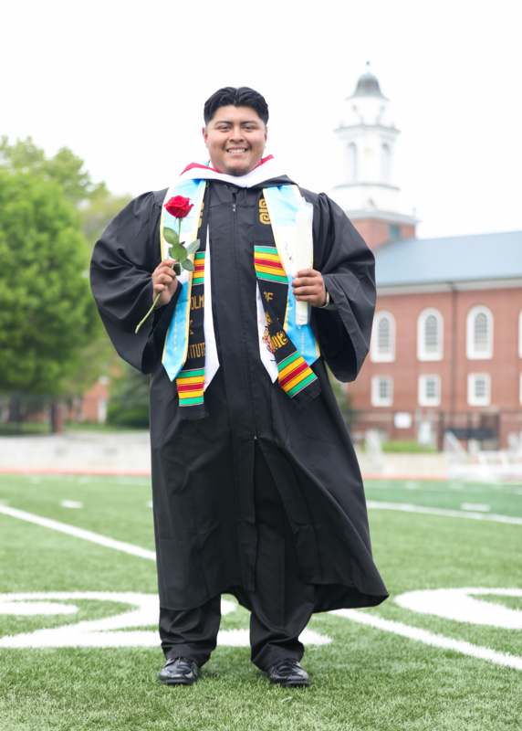 a man in a graduation gown holding a rose