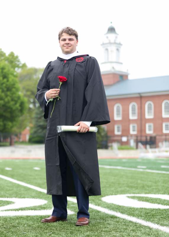 a man in a graduation gown holding a rose