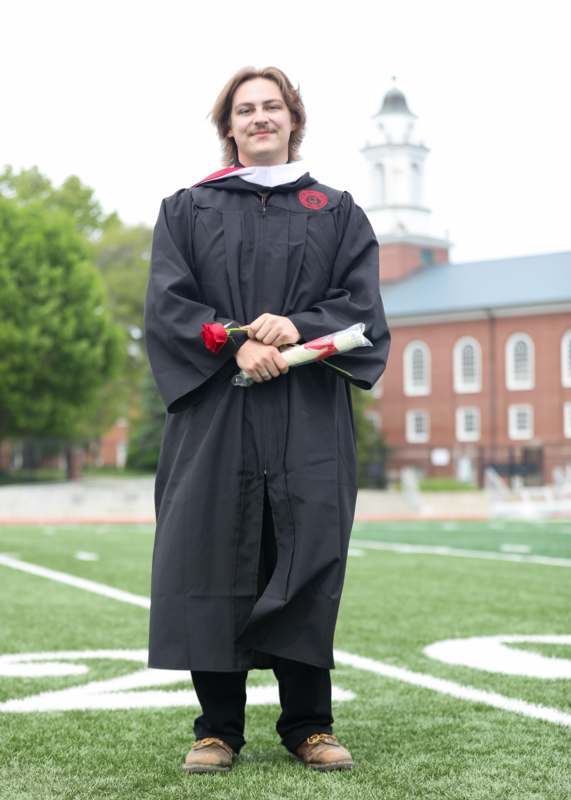 a person in a graduation gown holding a rose
