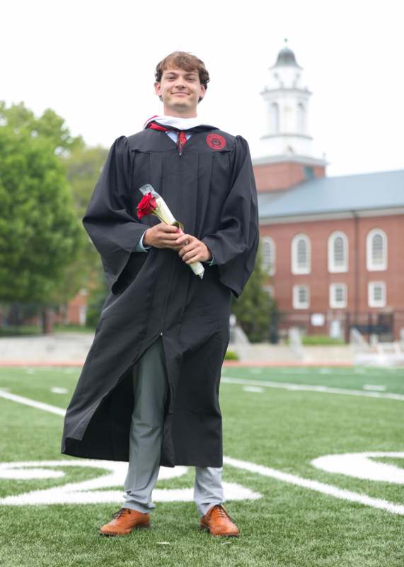 a man in a graduation gown holding flowers