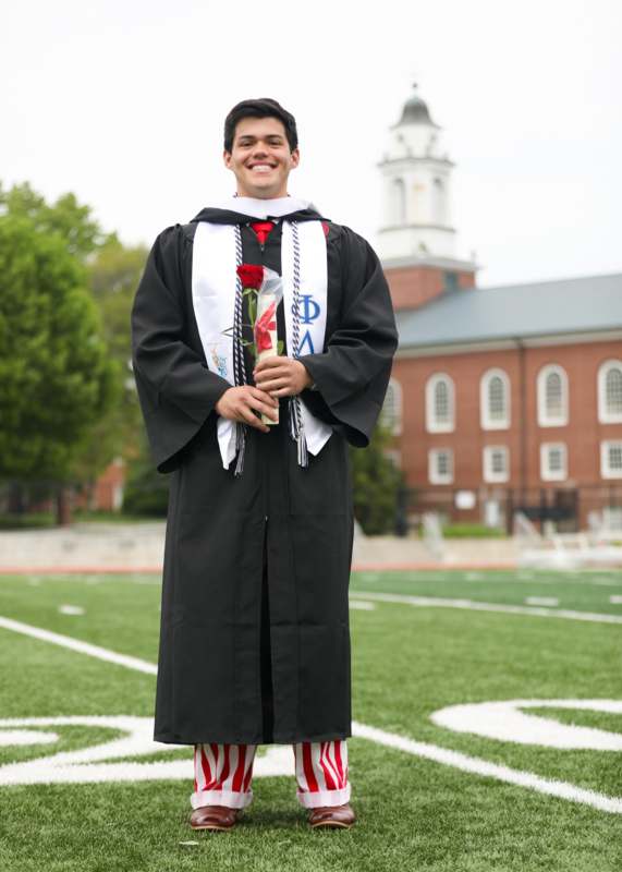 a man in a graduation gown holding a rose