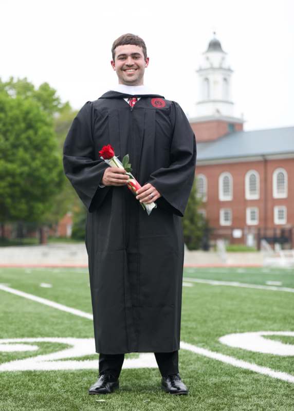 a man in a graduation gown holding a rose