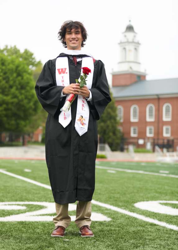a man in a graduation gown holding a rose