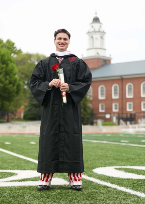 a man in a graduation gown holding a rose