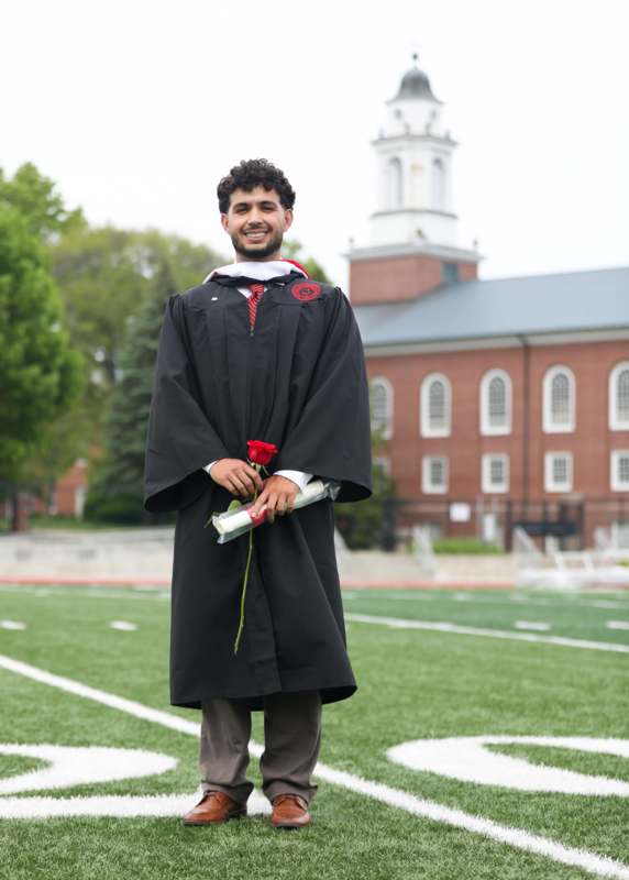 a man in a graduation gown holding a rose