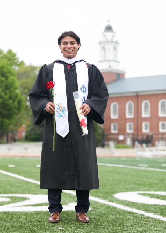 a man in a graduation gown holding a rose