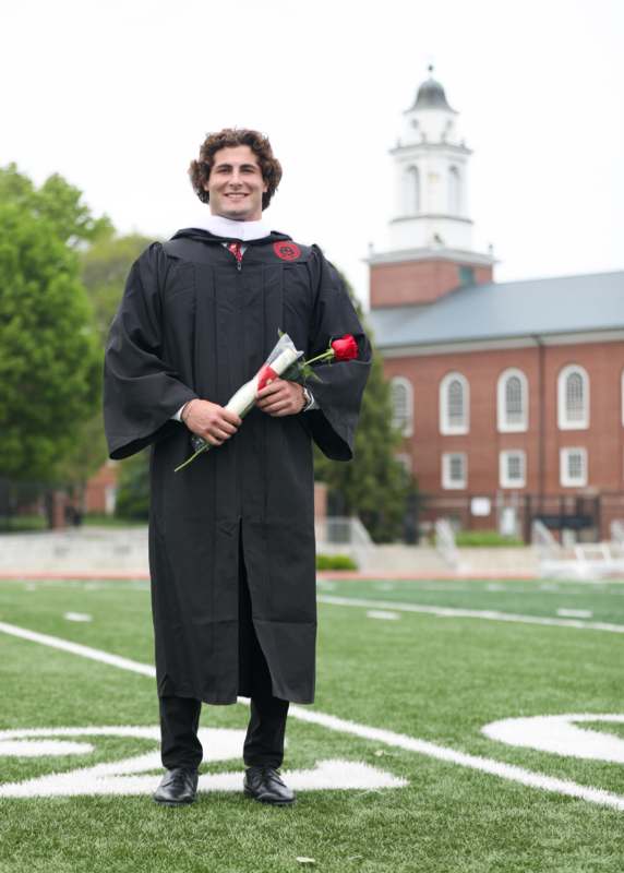 a man in a graduation gown holding a rose