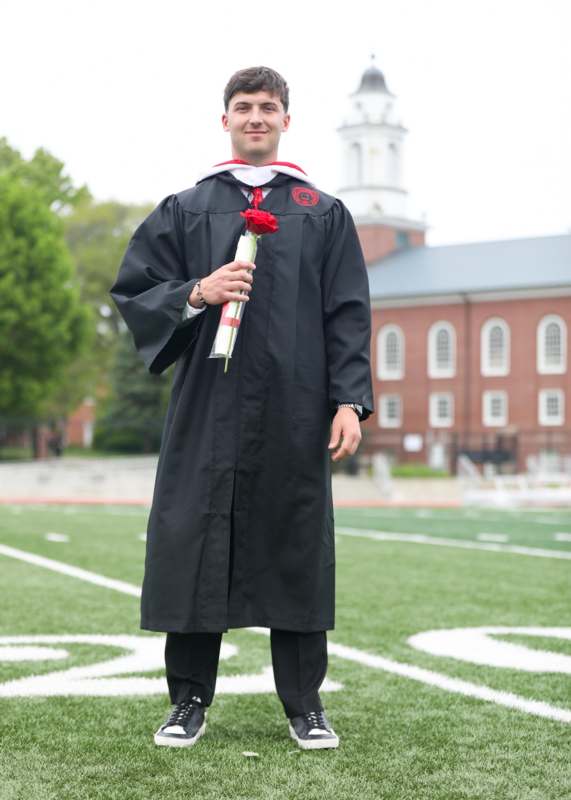 a man in a graduation gown holding a rose