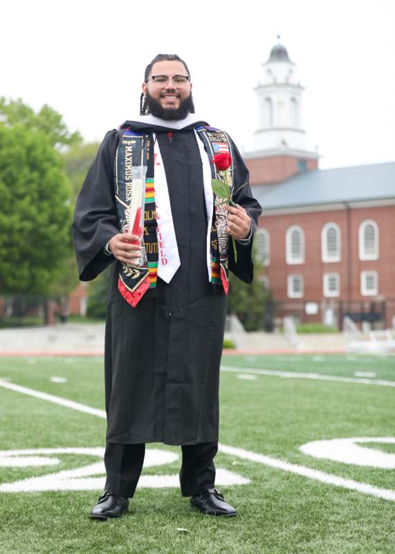 a man in a graduation gown holding a rose