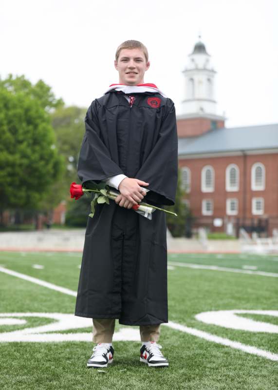 a man in a graduation gown holding a rose