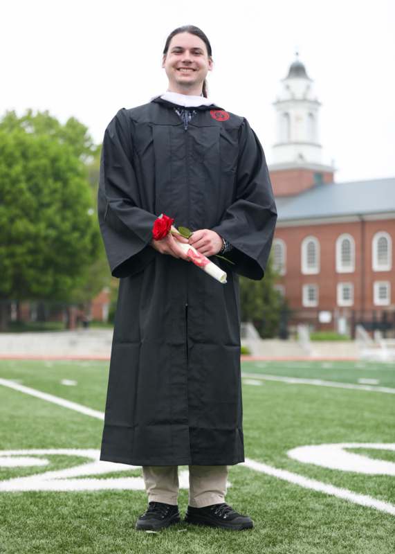 a man in a graduation gown holding a rose