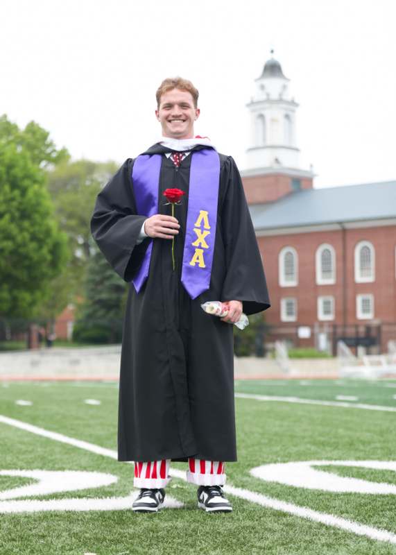 a man in a graduation gown holding a rose