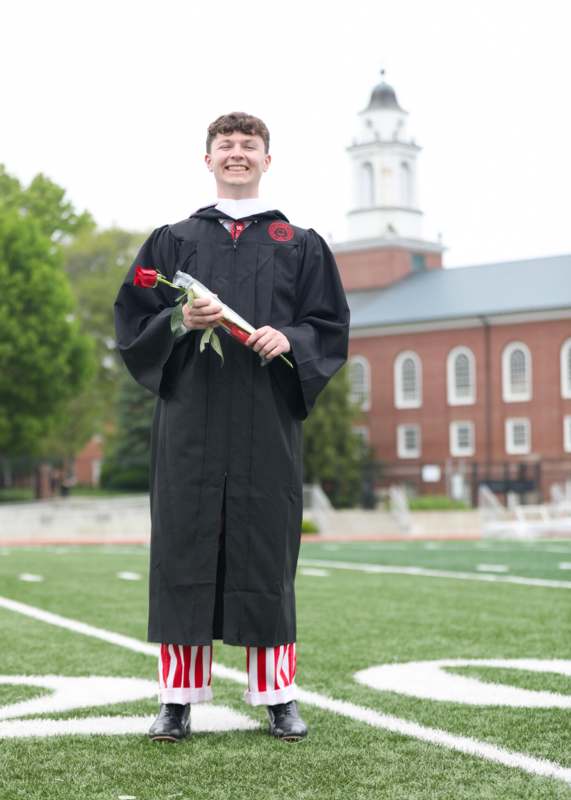 a man in a graduation gown holding a rose