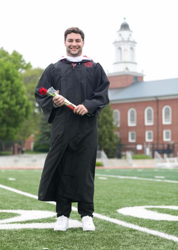 a man in a graduation gown holding a rose