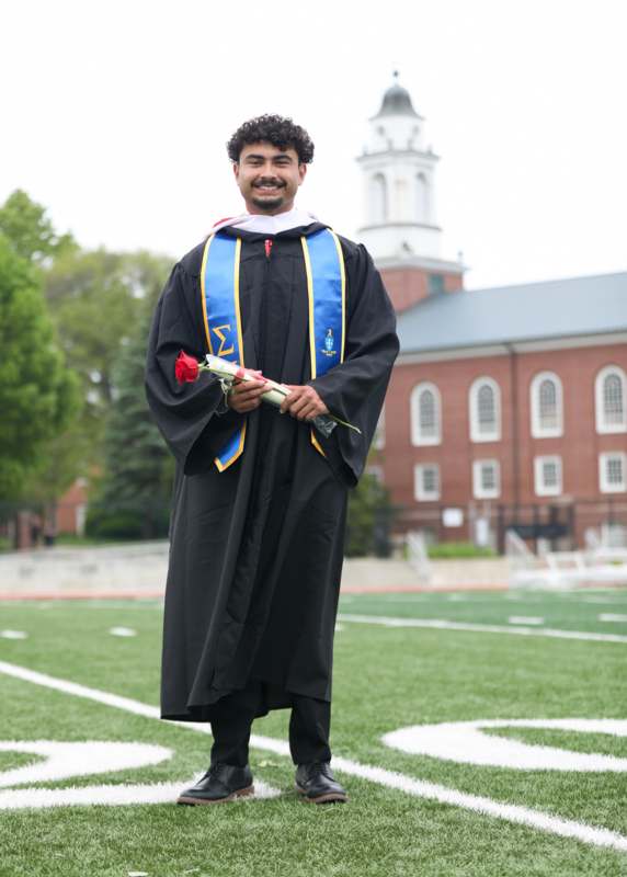 a man in a graduation gown holding a rose