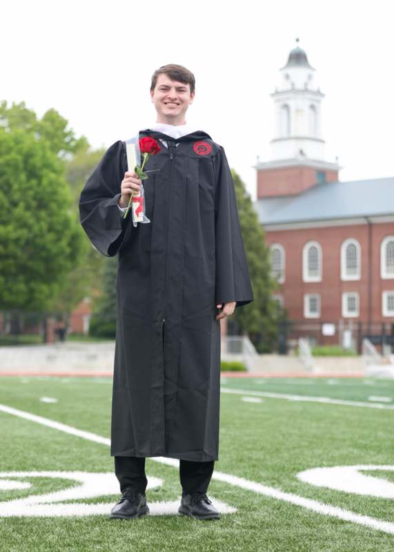 a man in a graduation gown holding a rose