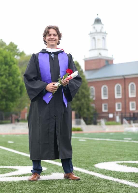 a man in a graduation gown holding a rose