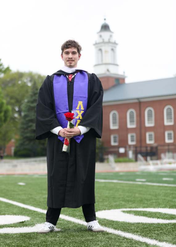a man in a graduation gown holding a rose