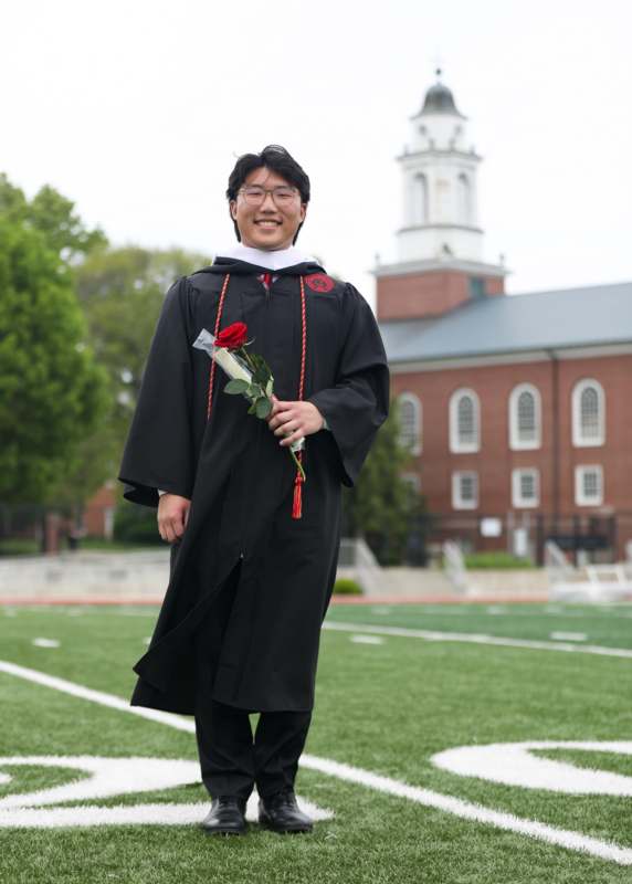 a man in a graduation gown holding a rose