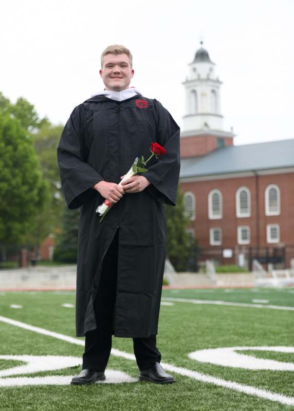 a man in a graduation gown holding a rose