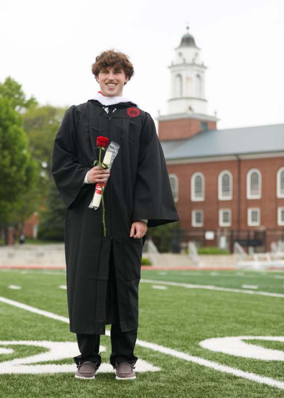 a man in a graduation gown holding a rose