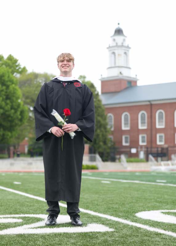 a man in a graduation gown holding a rose