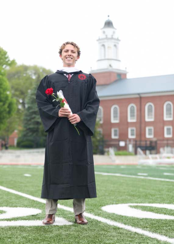 a man in a graduation gown holding a rose