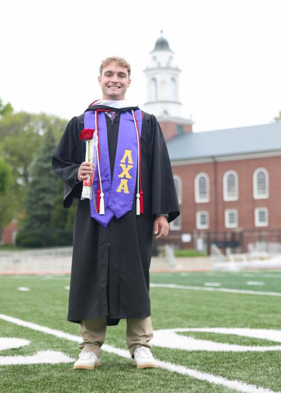 a man in a graduation gown holding a rose