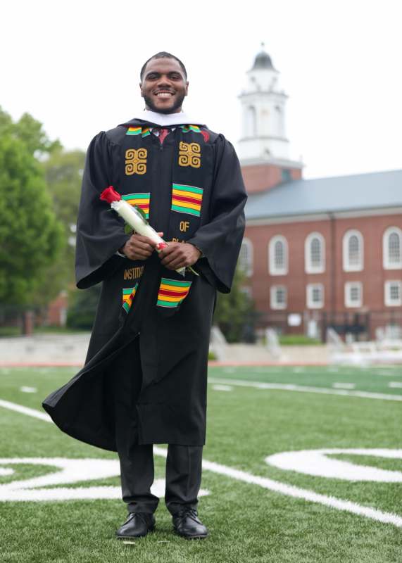 a man in a graduation gown holding a diploma
