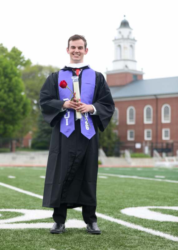 a man in a graduation gown holding a rose