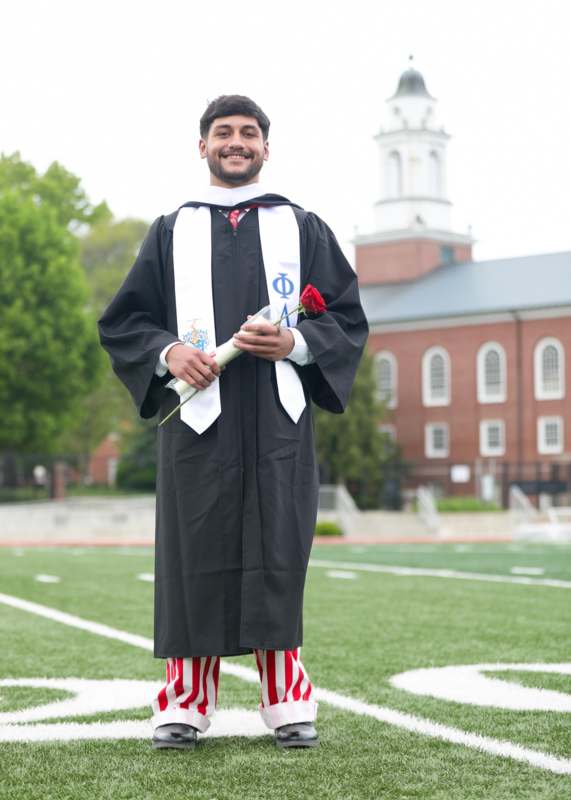 a man in a graduation gown holding a rose