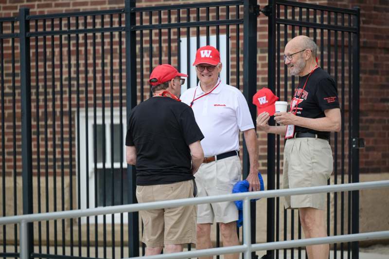a group of men standing in front of a fence