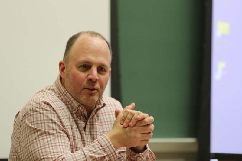 a man sitting in front of a green board